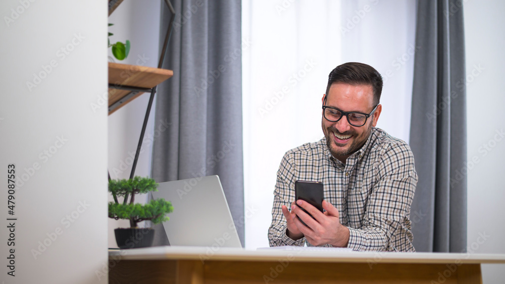 Smiling young manager working from home sending message to friend or coworker during break. Working at home during corona virus lock down Smiling young manager working from home sending message to friend or coworker during break. Working at home during corona virus lock down