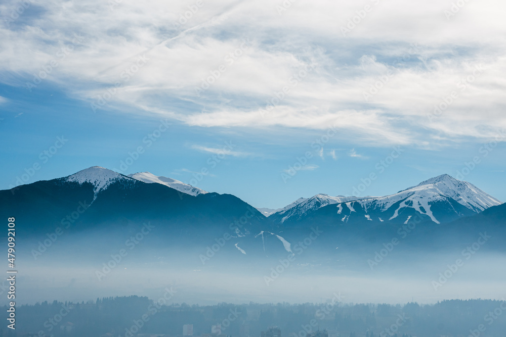 Fototapeta Pirin mountain, Bulgaria. Covered in snow peak in winter skiing season. Mist fog below the mountain. Blue cloudy sky.