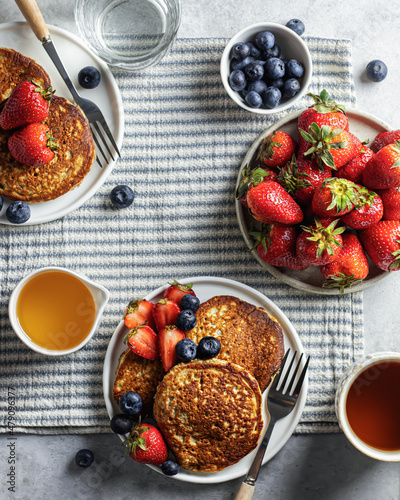Pancakes with berries on a striped breakfast tablecloth. Top view