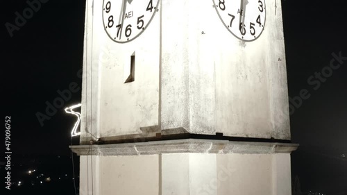 Medieval Italian catholic church belfry with clocks and bells at night winter time photo