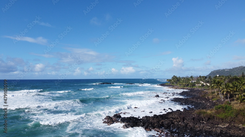 Oceanview coastline waves crashing into rocks  blue clear skies landscape view drone in Hawaii