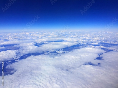 The view from the airplane window from above to the mountains, desert, rivers Airplane wing flying above the clouds. Cloud and sky pastel colors abstract nature background. airplanes and green