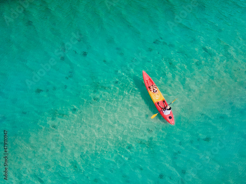 A bird's-eye view of a woman kayaking in the middle of the sea