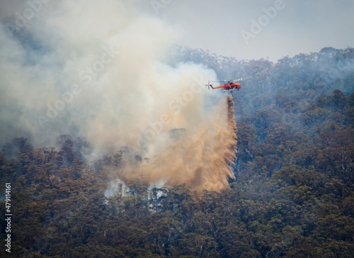 Photography A firefighting helicopter puts out fire from the smoking forest below