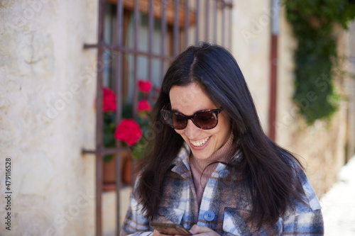 Smiling girl with sunglasses looking at smartphone