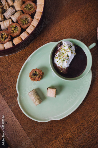 drinking chocolate in matching green cup and plate with assorted baklava desserts on wood table
