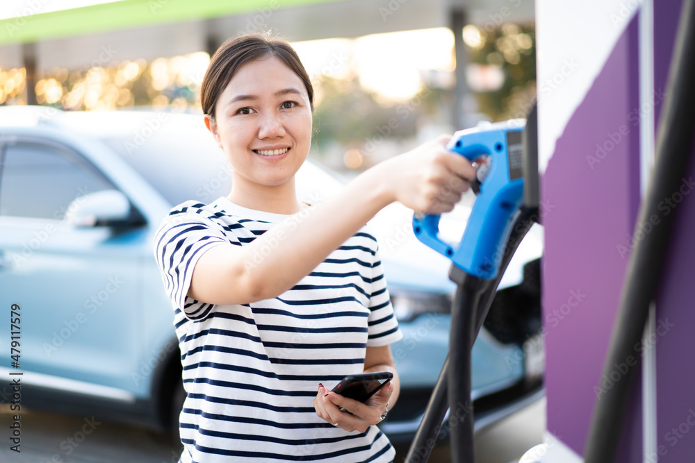 Unrecognizable Asian woman holding a DC - CCS type 2 EV charging ...