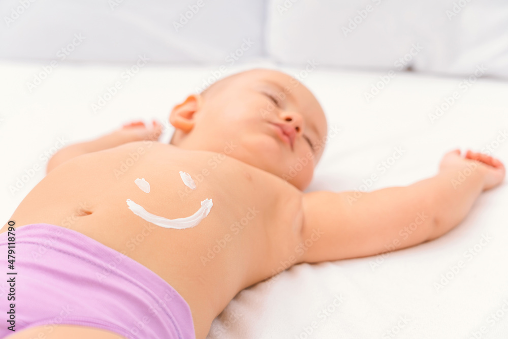 Sleeping baby with a smile painted with moisturizer on his stomach Sleeping baby with a smile painted with moisturizer on his stomach