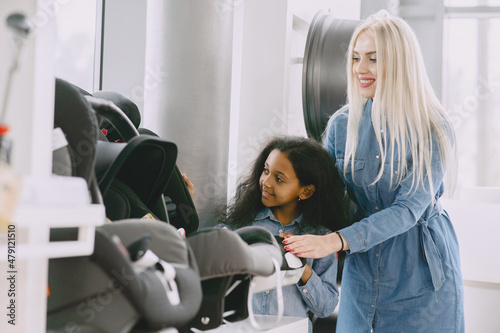 Caucasian mother with african daughter in a car salon