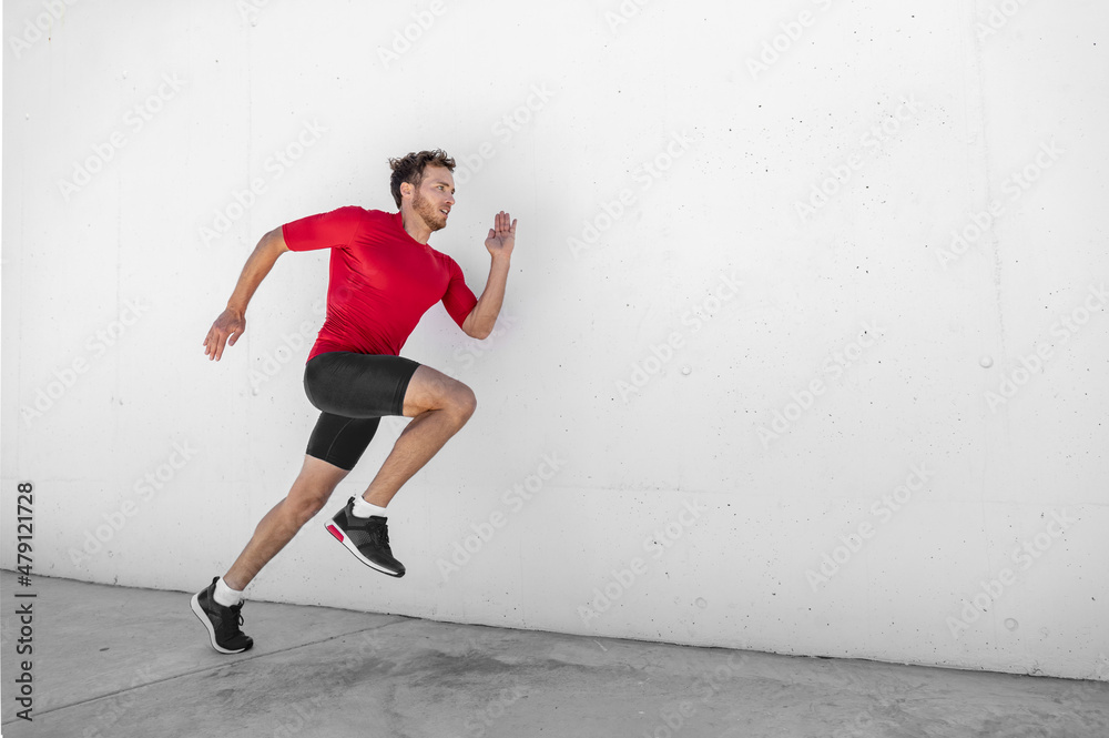 Sport athlete training running fast with explosive sprint for competition. Man runner working out at fitness gym outdoor white wall background.