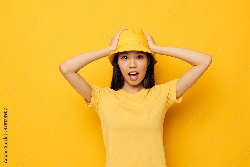 woman with Asian appearance in a yellow t-shirt and hat posing emotions isolated background unaltered woman with Asian appearance in a yellow t-shirt and hat posing emotions isolated background unaltered
