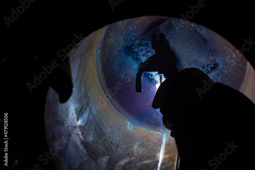 Close-up of a welder working in a workshop. Welding inside a metal structure.