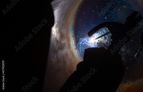 Close-up of a welder working in a workshop. Welding inside a metal structure.