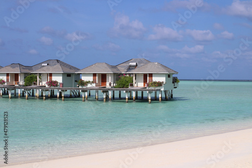 Morning in the Maldives, Indian Ocean shore with white sand, corals and villas over azure water
