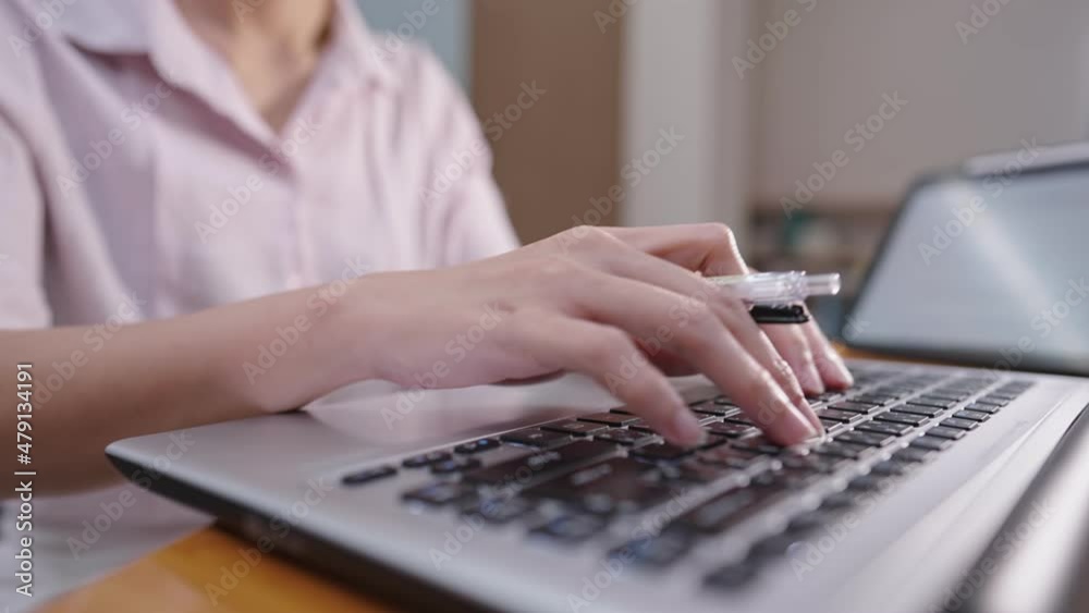 Close up female accountant worker working with laptop computer typing on keyboard while the hand holding pen, finance management workaholic lady, multitask working woman, deadline work overtime alone Close up female accountant worker working with laptop computer typing on keyboard while the hand holding pen, finance management workaholic lady, multitask working woman, deadline work overtime alone
