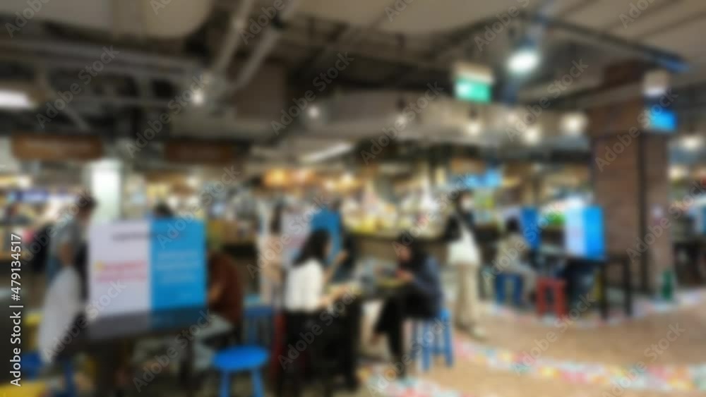 People walking in the food court of a shopping mall. It is a blurry image that prevents people's faces from being clearly visible and the labels of the products in department stores are not visible. People walking in the food court of a shopping mall. It is a blurry image that prevents people's faces from being clearly visible and the labels of the products in department stores are not visible.