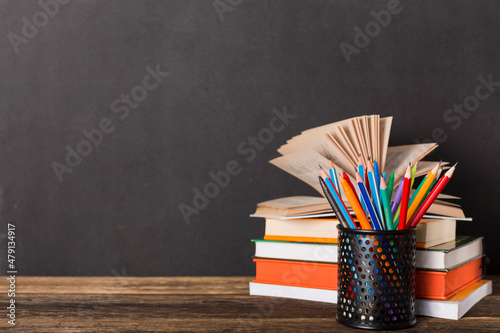 Stack of books and stationery on the background of the school board. Education and back to school concept.