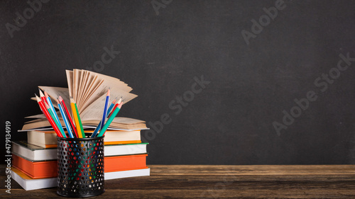 Stack of books and stationery on the background of the school board. Education and back to school concept. photo