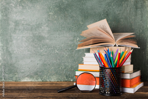 Stack of books and stationery on the background of the school board. Education and back to school concept.