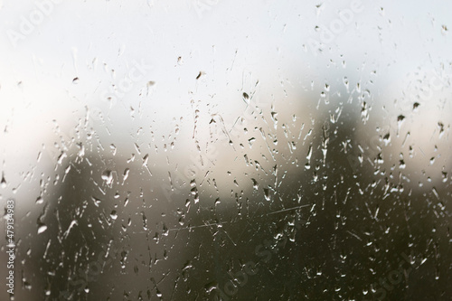 Window glass splattered with raindrops, abstract background, rainy weather