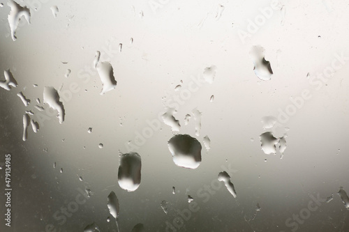 Window glass splattered with raindrops, abstract background, rainy weather