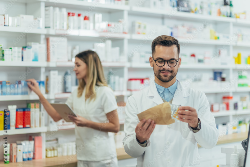 Male pharmacist packing drugs in a paper bag while working at a pharmacy