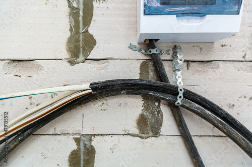 Image with focus view on the electrical power cables fixed on the wall made from foamed concrete block during the building house on the construction site. Cable prepared to installing to electrical