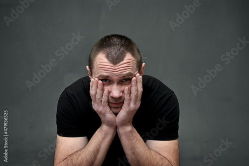 portrait of a large man man on a gray background looking at the camera in despair