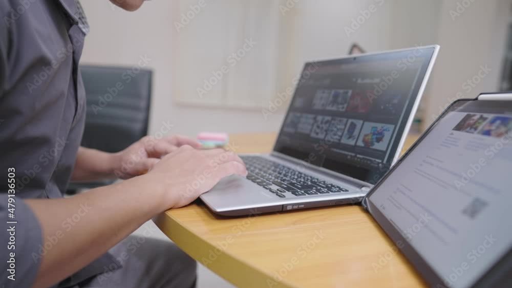 Young man using laptop computer searching for the electronics equipment for new office, salary man working with laptop, online shopping e-commerce, online purchasing, multitasking man work in office Young man using laptop computer searching for the electronics equipment for new office, salary man working with laptop, online shopping e-commerce, online purchasing, multitasking man work in office