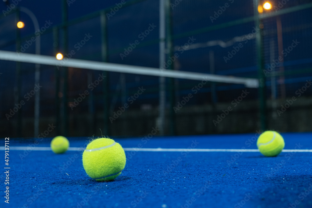 Selective focus. Three paddle tennis balls on the surface of a blue paddle tennis court.