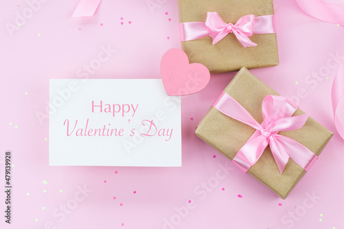 Happy Valentine's day greeting in English card on pink background with wrapped in craft paper presents © Eugenia