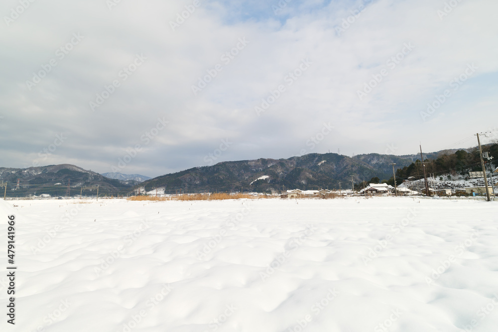 In Shiga Prefecture, Japan, in the middle of winter, a landscape of snow-covered plains and a small hut standing there.