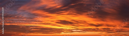 Sunset from bright saturated clouds. Dramatic sunset-sunrise with a pronounced texture of clouds without a horizon. Panorama of the evening sky with rich contrast of colors