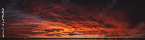 Sunset from bright saturated clouds. Dramatic sunset-sunrise with a pronounced texture of clouds and reflections on the horizon. Panorama of the evening sky with rich contrast of colors © Taras Rudenko