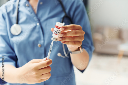 Test tube with vaccine. Young female doctor in uniform is indoors