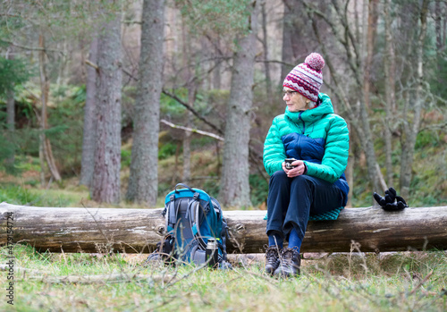 Single elderly woman resting during walking in forest during lockdown for good mental and physical health photo