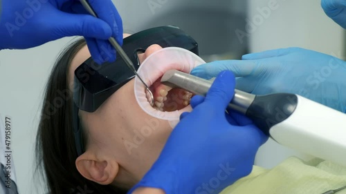 Dentist is doing intraoral scanning for woman before installing ceramic veneers and crowns. Orthodontist holds in his hand a manual 3D scanner for the jaw and mouth. Prosthodontics concept.