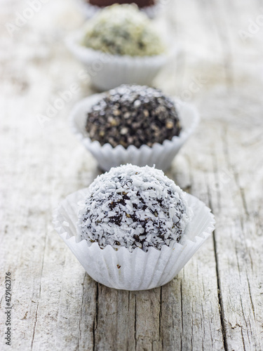 Energy protein balls with healthy ingredients on white wooden background. Home made with dates, peanut butter, flax and chia seeds, oats, almond and chocolate drops