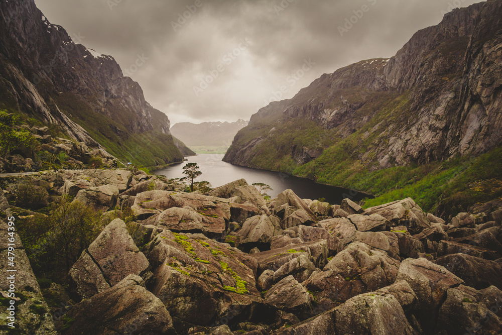 Beautiful fjord view in Norway with rock boulders and valley on a clouded day.
