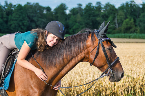 Portrait of a caucasian teenage girl, hugging her bay horse.