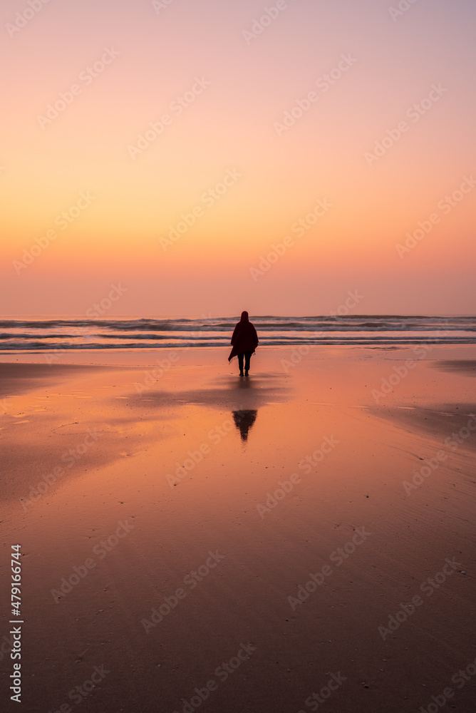 one person standing on the the beach in sunrise