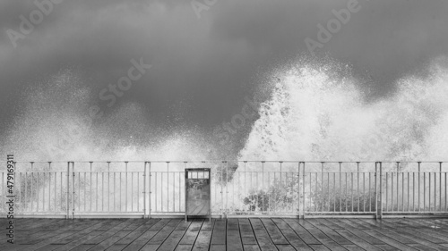stormy waves crashing against railings against the gray stormy sky