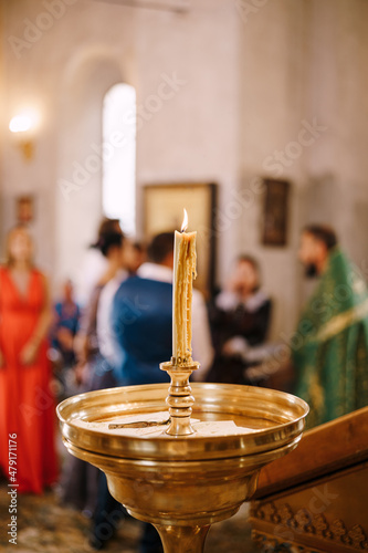 Wax candle burns on a stand in a large bowl in a temple