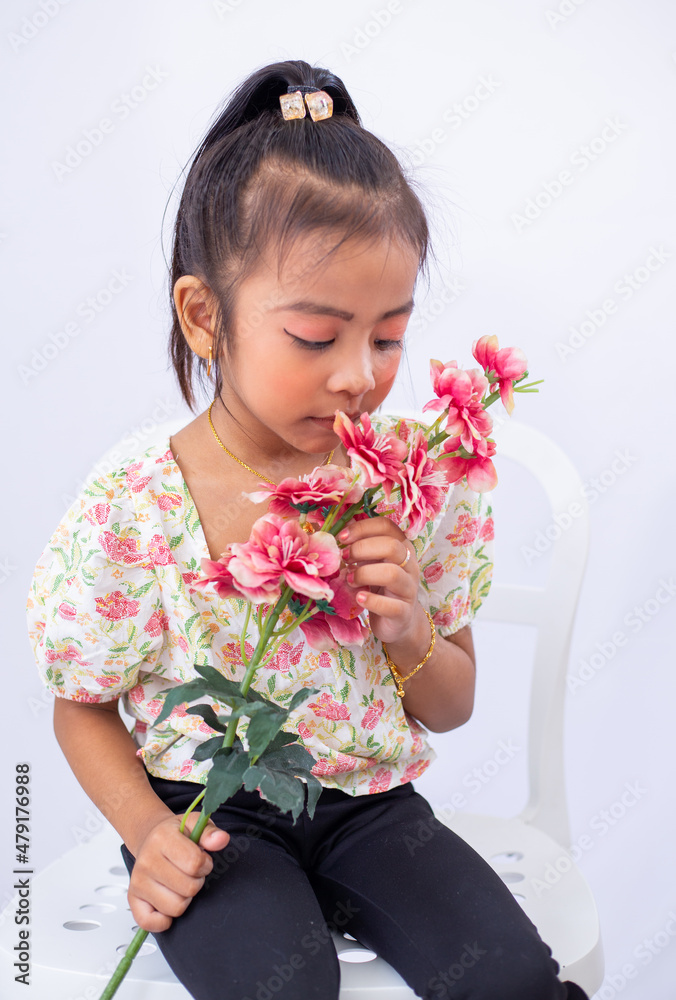 Little adorable asian girl sitting on a white chair, holding flower isolated on white background. Little adorable asian girl sitting on a white chair, holding flower isolated on white background.