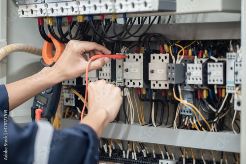 Electrician engineer work tester measuring voltage and current of power electric line in electical cabinet control   concept check the operation of the electrical system .