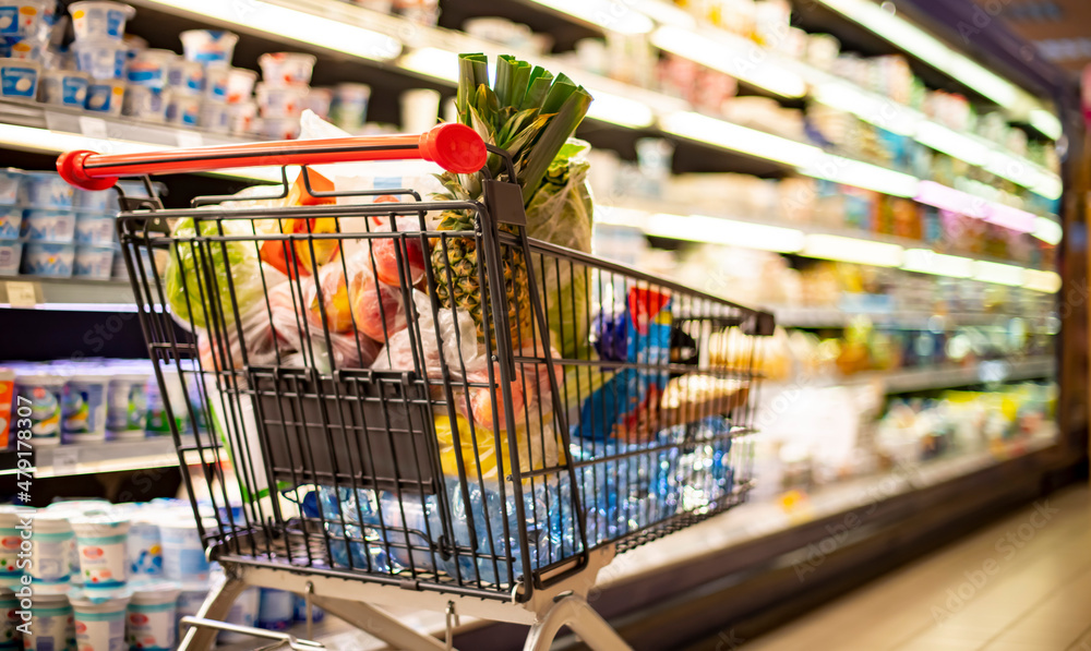 A shopping cart with grocery products in a supermarket