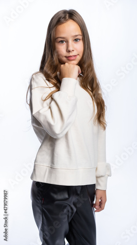 portrait of a girl in the studio. beautiful little girl in a white sweatshirt and trousers is smiling. isolated white background