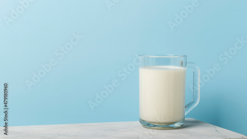 Milk in glass and cup on marble table and blue background with copy space for text.