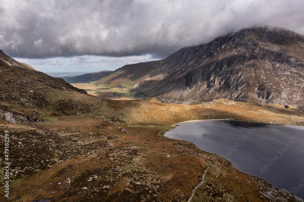 Aerial view of flying drone Epic landscape image in Autumn looking down Nant Fracon valley from Llyn Idwal with moody sky and copyspace
