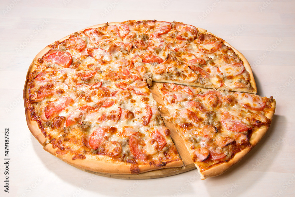 Fresh baked tasty sliced pizza with cheese meat and tomatoes